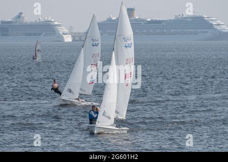 St. Petersburg, Russland, 27. Juli 2018: Yachten der 470-Klasse im Finnischen Meerbusen gegen große, in der Hafenfassade verankerte Kreuzschiffe Stockfoto