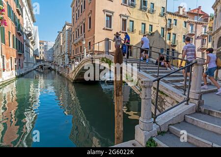 Touristen, die über eine der vielen kleinen Buckel Brücken in und um Venedig in Italien Stockfoto