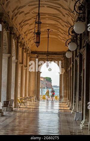 Am frühen Morgen baden die Sonnenstrahlen die Bögen der Biblioteca Nazionale Marciana (Nationalbibliothek des Hl. Markus) in Venedig, Norditalien Stockfoto