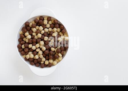 Schokolade und Vanille Müslischale isoliert auf weißem Hintergrund, Schokoladenkugeln, gesundes Frühstück Stockfoto