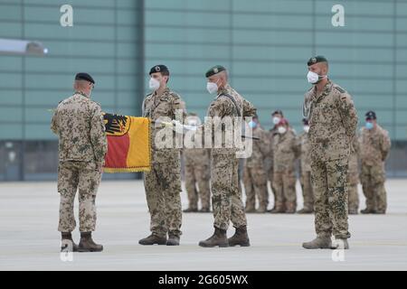 Wunstorf, Deutschland. 30. Juni 2021. Brigadegeneral Ansgar Meyer (l.), der letzte Kommandant der Bundeswehr in Afghanistan, rollt die Truppenflagge vor dem Transportflugzeug Airbus A400M der Luftwaffe. Die letzten Soldaten der deutschen Afghanistan-Mission sind auf dem Luftstützpunkt in Niedersachsen angekommen. Die Mission war am Vorabend nach fast 20 Jahren beendet. Die Soldaten waren mit vier Militärflugzeugen aus dem Feldlager in Masar-i-Sharif im Norden Afghanistans geflogen. Quelle: Hauke-Christian Dittrich/dpa-Pool/dpa/Alamy Live News Stockfoto