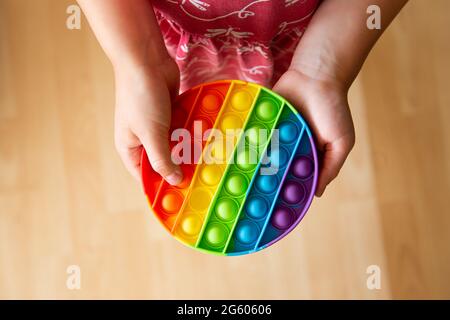 Nahaufnahme des kindlichen Spiels mit Regenbogenfarben beliebten Push-Pop-Blase sensorischen Fidget Spielzeug. Stockfoto