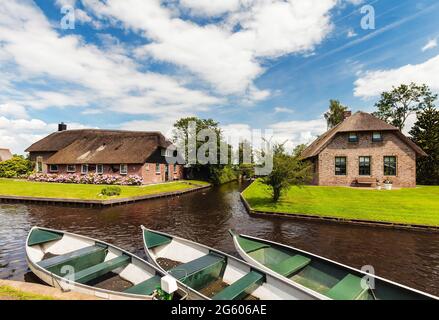 Kleine Kanalkreuzfahrtschiffe vor alten Häusern im niederländischen Dorf Giethoorn Stockfoto