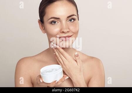 Beauty Gesicht der Frau Konzept. Hautpflege. Porträt des weiblichen Modells halten und Anwendung kosmetische feuchtigkeitsspendende Creme und berühren Sie eigenes Gesicht. Hautschutzkol Stockfoto
