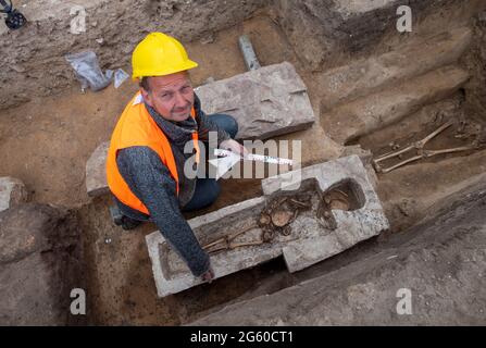 Eisleben, Deutschland. Juli 2021. Projektleiter und Archäologe Felix Biermann untersucht einen Sarkophag auf dem Gelände des ehemaligen Königspalastes von Helfta. Archäologen des Landesamtes für Denkmalpflege und Archäologie Sachsen-Anhalt hatten bereits vor Wochen damit begonnen, die Grundmauern der Kirche Kaiser Ottos des Großen (912-973) aufzudecken. Dabei stießen die Archäologen auf eine große Anzahl von Bestattungen, darunter mehrere Steinkrypten aus dem 10. Bis 15. Jahrhundert. Quelle: dpa picture Alliance/Alamy Live News Stockfoto