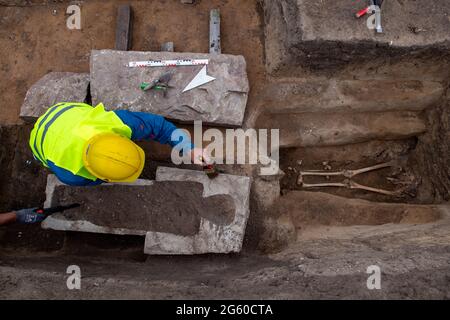 Eisleben, Deutschland. Juli 2021. Ein Grabungsarbeiter untersucht einen Sarkophag an der Stelle des ehemaligen königlichen Palastes von Helfta. Archäologen des Landesamtes für Denkmalpflege und Archäologie Sachsen-Anhalt hatten bereits vor Wochen damit begonnen, die Grundmauern der Kirche Kaiser Ottos des Großen (912-973) aufzudecken. Dabei stießen die Archäologen auf eine große Anzahl von Bestattungen, darunter mehrere Steinkrypten aus dem 10. Bis 15. Jahrhundert. Quelle: dpa picture Alliance/Alamy Live News Stockfoto