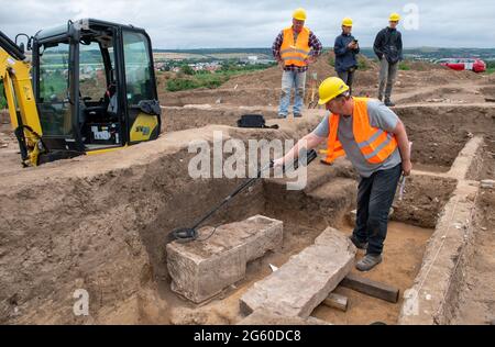 Eisleben, Deutschland. Juli 2021. Projektleiter und Archäologe Felix Biermann untersucht mit einem Metalldetektor einen Sarkophag auf dem Gelände des ehemaligen Königspalastes Helfta. Archäologen des Landesamtes für Denkmalpflege und Archäologie Sachsen-Anhalt hatten bereits vor Wochen damit begonnen, die Grundmauern der Kirche Kaiser Ottos des Großen (912-973) aufzudecken. Dabei stießen die Archäologen auf eine große Anzahl von Bestattungen, darunter mehrere Steinkrypten aus dem 10. Bis 15. Jahrhundert. Quelle: dpa picture Alliance/Alamy Live News Stockfoto