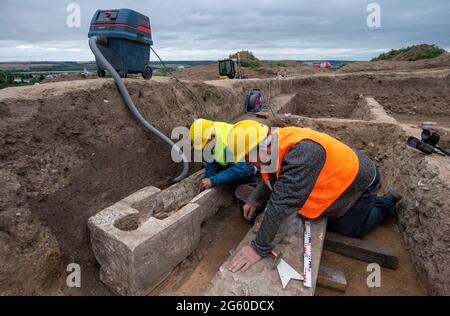 Eisleben, Deutschland. Juli 2021. Archäologen untersuchen einen Sarkophag an der Stelle des ehemaligen königlichen Palastes von Helfta. Archäologen des Landesamtes für Denkmalpflege und Archäologie Sachsen-Anhalt hatten bereits vor Wochen damit begonnen, die Grundmauern der Kirche Kaiser Ottos des Großen (912-973) aufzudecken. Dabei stießen die Archäologen auf eine große Anzahl von Bestattungen, darunter mehrere Steinkrypten aus dem 10. Bis 15. Jahrhundert. Quelle: dpa picture Alliance/Alamy Live News Stockfoto