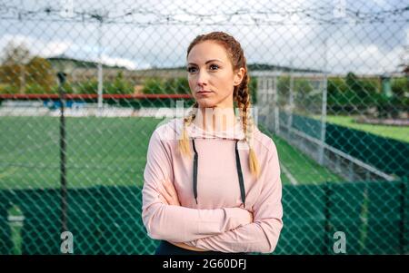 Seriöse Sportlerin mit Boxergeflechten, die mit gekreuzten Armen posiert Stockfoto