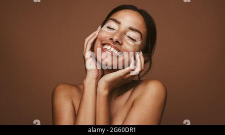 Nahaufnahme einer lächelnden jungen Frau mit Vitiligo. Porträt einer Frau mit Hautproblem in glückseliger Stimmung auf braunem Hintergrund. Stockfoto