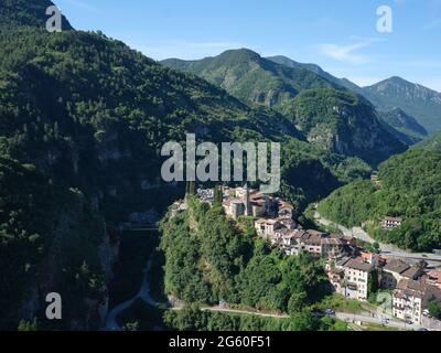 LUFTAUFNAHME. Das Dorf Lantosque liegt in einem tiefen und engen bewaldeten Tal und blickt flussabwärts. Vésubie Valley, Alpes-Maritimes, Frankreich. Stockfoto