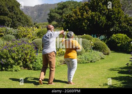 afroamerikanisches Senioren-Paar, das gemeinsam im sonnigen Garten tanzt Stockfoto