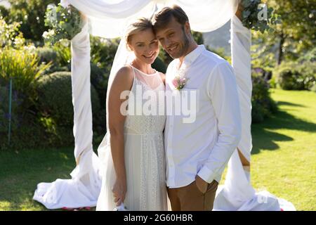 Porträt einer glücklichen kaukasischen Braut und eines Bräutigams, die heiraten und umarmen Stockfoto