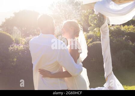 Glückliche kaukasische Braut und Bräutigam heiraten und umarmen Stockfoto