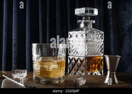 Whiskey in Felsen und Flasche auf dunkelblauem Vorhang Hintergrund. Feiertagsfeier. Nahaufnahme. Stockfoto
