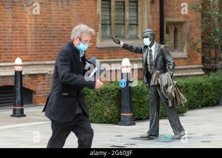 Ein Mann geht in LondonIn den letzten Wochen an einer Statue vorbei, die eine Maske trägt.in Großbritannien ist die Zahl der bestätigten Covid-Fälle gestiegen und hat die höchste seit der Wiedereröffnung der Wirtschaftstätigkeit erreicht. Zu den Anstiegen gehört das Aufkommen einer neuen Variante des COVID 19-Virus, bekannt als indische Variante oder Delta-Variante. Während die Menschen ausgehen und sich an alltäglichen Aktivitäten beteiligen, als ob COVID vorüber wäre, werden Restaurants und Polizeibeamte immer noch beobachtet, dass sie soziale Distanzierungsmaßnahmen beibehalten, um den jüngsten Anstieg zu mildern, der durch den zunehmenden Kontakt mit der Stadt verursacht wurde. ( Stockfoto