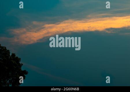 Extrem schöne blaue und orange Wolken mit etwas Mahagoni Blatt und Stiel Stockfoto