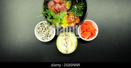 Salat mit Thunfisch in eine Schüssel geben. Zutaten frischer Thunfisch, Kirschtomaten, marinierte Algen, Reis, Takuan, Ponzu-Sauce, Teriyaki-Sauce, Nori, Sesam Stockfoto