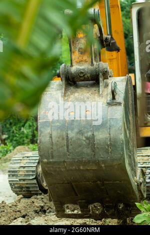 Der Bagger ist ein schweres Fahrzeug, das auf einer Straße für Ausgrabungen arbeitet Stockfoto