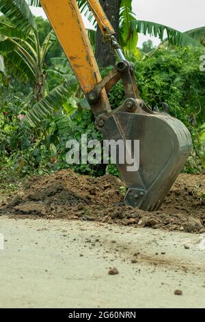 Der Bagger, der auf der Baustelle arbeitet und mit einem Arbeiter arbeitet Stockfoto