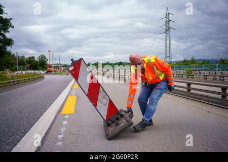 Wiesbaden, Deutschland. Juli 2021. Ein Verkehrssicherheitsmitarbeiter richtet die Ausfahrt in Richtung Wiesbaden ein. Die Autobahn GmbH West hat an der baufälligen Salzbachtal-Brücke eine sogenannte Umgehungsstraße eröffnet. Die Bundesstraße B263 kann nun wieder mit einer Spur in jede Richtung genutzt werden. Quelle: Andreas Arnold/dpa/Alamy Live News Stockfoto