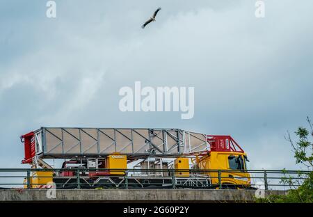 Wiesbaden, Deutschland. Juli 2021. Ein Storch kreist über einem Baufahrzeug auf der baufälligen Salzbachtalbrücke. Die Autobahn GmbH West hat an der baufälligen Salzbachtalbrücke eine sogenannte Umgehungsstraße eröffnet. Die Bundesstraße B263 kann nun wieder mit einer Spur in jede Richtung genutzt werden. Quelle: Andreas Arnold/dpa/Alamy Live News Stockfoto