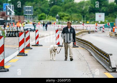 Wiesbaden, Deutschland. Juli 2021. Ein Pressevertreter spaziert mit dem Redaktionshund 'Lino' (10, Wachhund) über den geschlossenen Brückenkopf der Salzbachtalbrücke. Die Autobahn GmbH West hat an der angeschlagenen Salzbachtalbrücke eine sogenannte Umgehungsstraße eröffnet. Die Bundesstraße B263 kann nun wieder mit einer Spur in jede Richtung genutzt werden. Quelle: Andreas Arnold/dpa/Alamy Live News Stockfoto