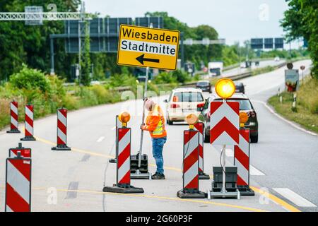 Wiesbaden, Deutschland. Juli 2021. Ein Verkehrssicherheitsmitarbeiter richtet die Ausfahrt in Richtung Wiesbaden ein. Die Autobahn GmbH West hat an der baufälligen Salzbachtal-Brücke eine sogenannte Umgehungsstraße eröffnet. Die Bundesstraße B263 kann nun wieder mit einer Spur in jede Richtung genutzt werden. Quelle: Andreas Arnold/dpa/Alamy Live News Stockfoto