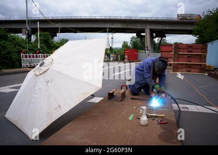 Wiesbaden, Deutschland. Juli 2021. Ein Bauarbeiter führt Schweißarbeiten auf der Baustelle an der Salzbachtalbrücke durch. Die Autobahn GmbH West hat an der baufälligen Salzbachtal-Brücke eine sogenannte Umgehungsstraße eröffnet. Die Bundesstraße B263 kann nun wieder mit einer Spur in jede Richtung genutzt werden. Quelle: Andreas Arnold/dpa/Alamy Live News Stockfoto