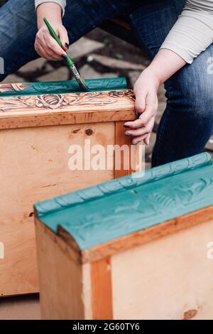 Nahaufnahme von Handgemalten Frauen, die antike Holzschubladen in blauen oder grünen recycelten Möbeln bemalen Stockfoto