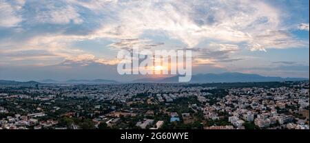 Sonnenuntergang über Athen, Griechenland. Luftdrohnen-Panoramablick vom Penteli-Berg. Letzte Sonnenstrahlen über der griechischen Hauptstadt. Reiseziel Athen, wo Sonnenstrahlen c Stockfoto