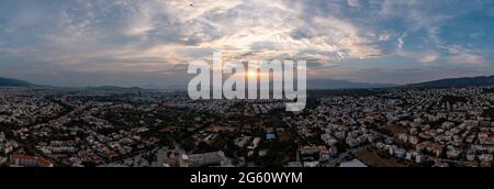 Sonnenuntergang über Athen, Griechenland. Luftdrohne Weitwinkelansicht vom Penteli Mount. Letzte Sonnenstrahlen über dem Hintergrund der griechischen Hauptstadt. Ziel, wo Sonnenstrahlen Stockfoto