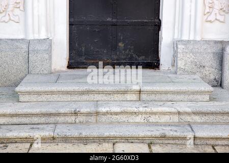 Granitschwelle an der Eingangstür aus schwarzem Rosteisen und weißer Fassade aus grauem Granit, ein altes Retro-Gebäude, Nahaufnahme von vorne, nein Stockfoto