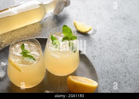 Heidselige organische probiotische hausgemachte Kombucha in Gläsern mit Zitrone und Ingwer auf grauem Hintergrund mit Kopierraum. Nahaufnahme. Stockfoto