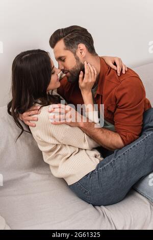 Seitenansicht des jungen Paares, das sich auf der Couch küsst und umarmt Stockfoto