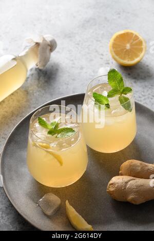 Heidselige organische probiotische hausgemachte Kombucha in Gläsern mit Zitrone und Ingwer auf grauem Hintergrund mit Kopierraum. Nahaufnahme. Vertikales Format. Stockfoto