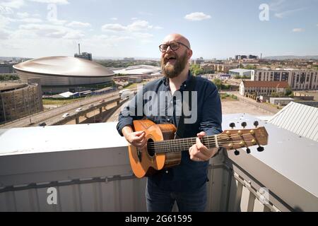 Der Musiker Findlay Napier probt auf dem Dach des Skypark in Glasgow mit dem Veranstaltungsort SSE Hydro als Kulisse, als er sich bereit macht, die ersten Skypark Music Sessions mit der Band Mt aufzunehmen. Zweifel und Musiker Daniel Meade. Die Sessions werden am 13,20. Und 27. August gestreamt, um neue Musik zu zeigen und Werbematerial zu geben, zu einer Zeit, in der Musiker nicht live spielen konnten. Bilddatum: Donnerstag, 1. Juli 2021. Stockfoto