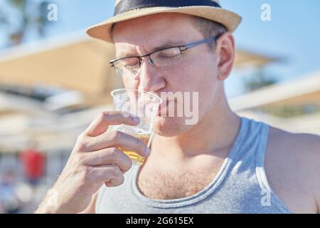 Der junge Kaukasusmann trinkt bei Sommerwetter am Strand ein Bier. Sommerferien Konzept. Stockfoto