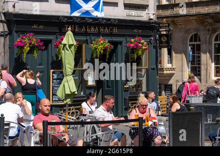 Edinburgh, Schottland, Großbritannien. Juli 2021. Warme Temperaturen und Sonnenschein zogen viele Besucher in die Straßencafés und Bars von Edinburgh und in das neue Einkaufszentrum des St. James Quarter, das letzte Woche eröffnet wurde. PIC; Trinker genießen die Sonne im Albanach auf der Royal Mile. Iain Masterton/Alamy Live News Stockfoto