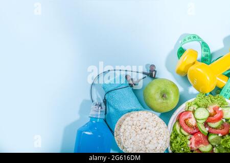 Sport gesunde Lebensweise, Diät-Konzept. Abnehmen Gewichtsverlust Fitness-Hintergrund mit Maßband, farbige Hanteln, Salat, Müsli knackig Brot, Spor Stockfoto