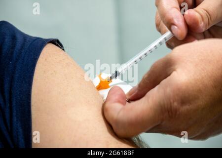 Nahaufnahme eines Arms eines Mannes, der einen Covid-19-Impfstoff angeschossen hat Stockfoto