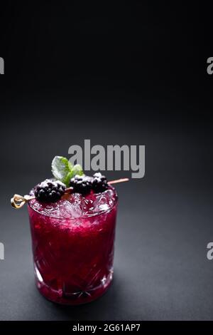 Nahaufnahme von Alkohol Heidelbeere speziellen Cocktail mit Brombeere in Weinglas Stockfoto