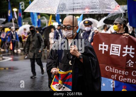 Tokio, Japan. Juli 2021. Ein Mönch mit der tibetischen Flagge und einem Regenschirm während der Demonstration am 1. Juli jährt sich die Gründung der KPCh (Kommunistische Partei Chinas) zum 100. Mal und der 24. Jahrestag der Übergabe Hongkongs an China. Anhänger der KPCh gingen auf die Straße, um zu feiern, während Demonstranten für Demokratie in Hongkong ebenfalls durch die Hauptstadt marschieren, um ihre politischen Standplätze auszudrücken. Kredit: SOPA Images Limited/Alamy Live Nachrichten Stockfoto