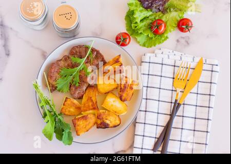 Draufsicht auf gegrillten Schweinehals mit gebratener Kartoffel, Tomaten und Cetcup auf hellem Hintergrund Stockfoto