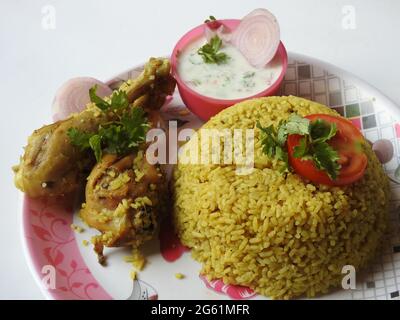 Biryani mit zwei Beinstücken und Joghurt tauchen in einen Teller isoliert auf weißem Hintergrund Stockfoto