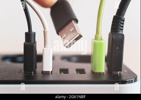 Modernes praktisches Multi-Port usb-Ladegerät für Geräte. Nahaufnahme von eingelegten mehrfarbigen Kabeln in einer Steckdose. Makro. Stockfoto