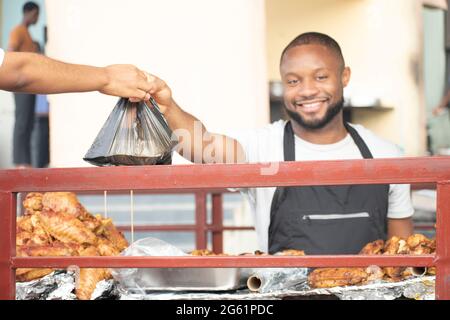 afrikanischer Mann, der gebratenes Huhn verkauft Stockfoto