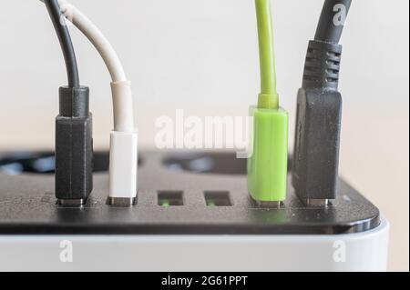 Modernes praktisches Multi-Port usb-Ladegerät für Geräte. Nahaufnahme von mehrfarbigen Kabeln in einer Steckdose. Makro. Angepflügt. Stockfoto