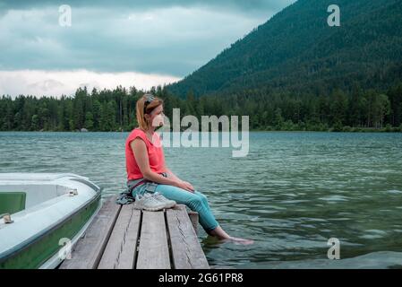 Junge Frau, die sich am Pier am See entspannt Stockfoto