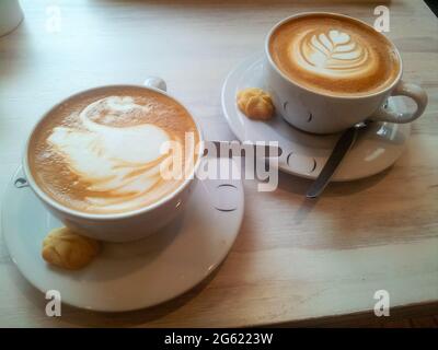 Der Latte Arts Coffee. Kaffee Art. Zwei heiße Kaffeesets in einer weißen Tasse auf Schreibtisch oder Tisch. Stockfoto